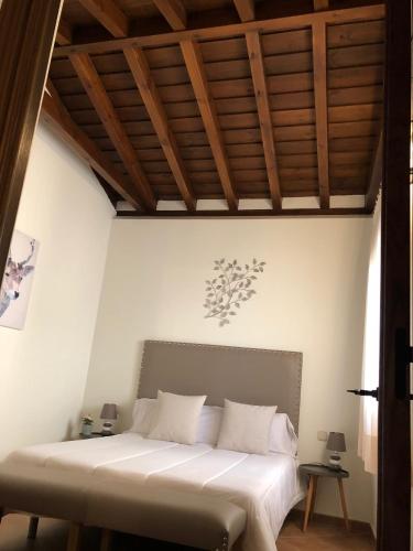 a bedroom with a white bed with a wooden ceiling at El Patrón in Chinchón