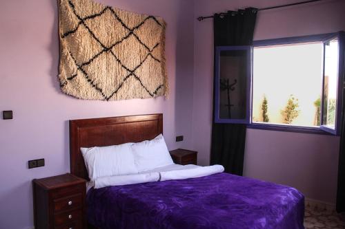a bedroom with a bed with purple sheets and a window at Dar Iziki in Sidi Kaouki