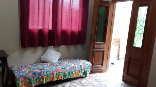 een kamer met een bed, rode gordijnen en een deur bij Suíte ampla com cozinha Ibitipoca in Conceição da Ibitipoca