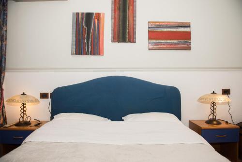 a bed with a blue head board and two lamps at DB Apartment in Tirana