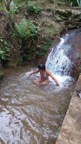 a woman is swimming in a river near a waterfall at Pousada Vertente das Águas in Lumiar