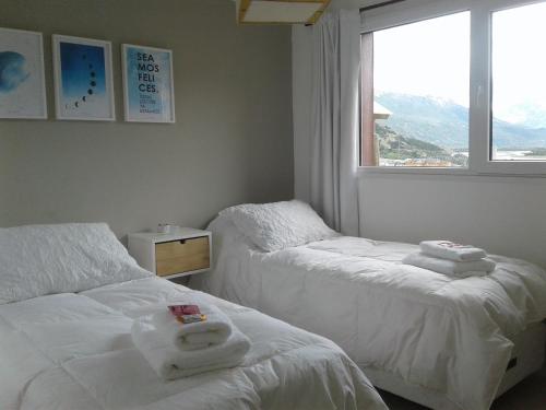 two beds in a room with a window at Mirador del Bosque Aparts in El Chalten