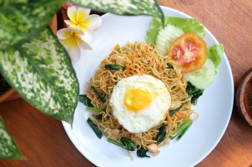 a plate of noodles with an egg on top at D'Pande Kuta in Kuta