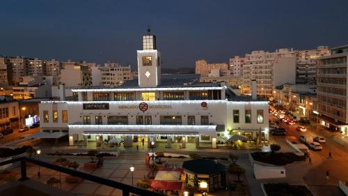 a large white building with a clock tower in a city at The Market Square House in Faro