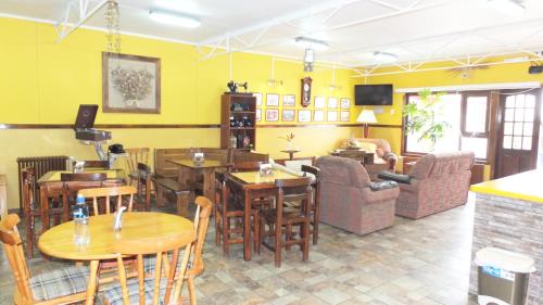 un restaurante con mesas, sillas y paredes amarillas en Hostal Maipu Street, en Punta Arenas
