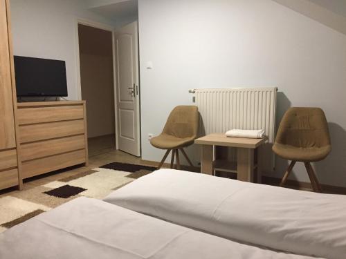 a bedroom with a bed and two chairs and a television at MOKKA PANZIÓ in Szarvas