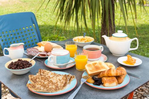 ein Tisch mit Tellern mit Frühstücksspeisen und Orangensaft in der Unterkunft The Originals City, Hôtel La Belle Étape, Brignoles in Brignoles