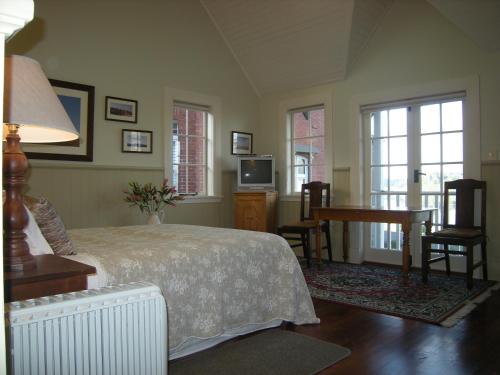 a bedroom with a bed and a desk and windows at Braestone Lodge in Dunedin