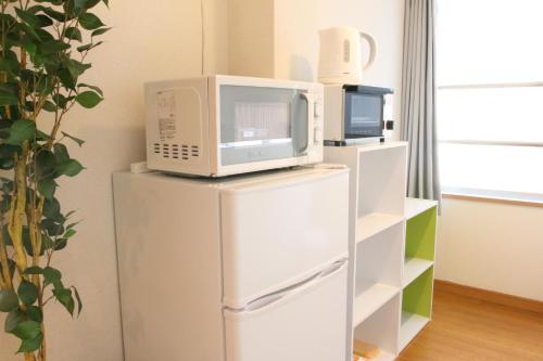 a microwave sitting on top of a refrigerator at Minoshima Apartment 406 in Fukuoka