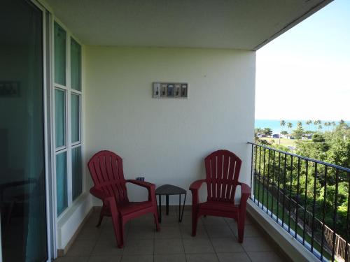 two red chairs and a table on a balcony at Sunset Paradise - Ocean View Penthouse Apartment in Cabo Rojo