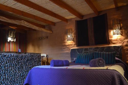 a room with a bed with blue pillows in it at Ckuri Atacama in San Pedro de Atacama