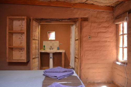 a bathroom with a sink and a bed in a room at Ckuri Atacama in San Pedro de Atacama