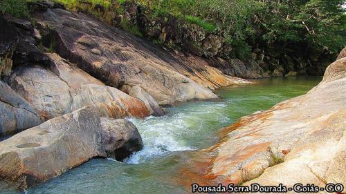 a river with rocks and green water and trees at Pousada Serra Dourada in Goiás