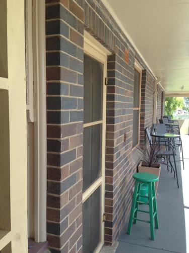 a brick wall with a door and a green stool at Walcha Royal Cafe & Accommodation in Walcha