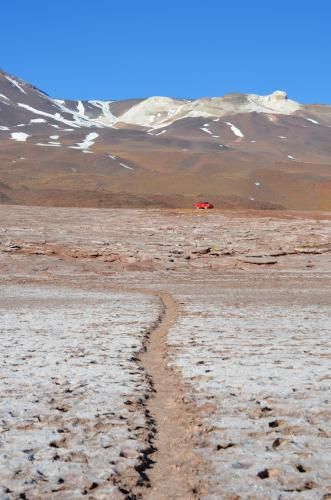 a road in the desert with a red car in the background at Ckuri Atacama in San Pedro de Atacama