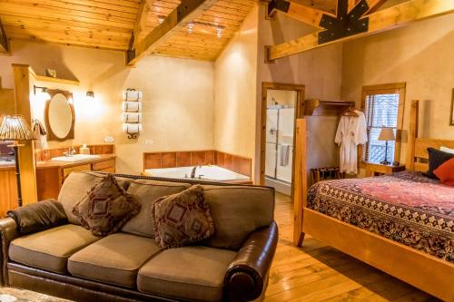 a living room with a couch and a bed and a tub at Riverside Cottage #26 in Ruidoso