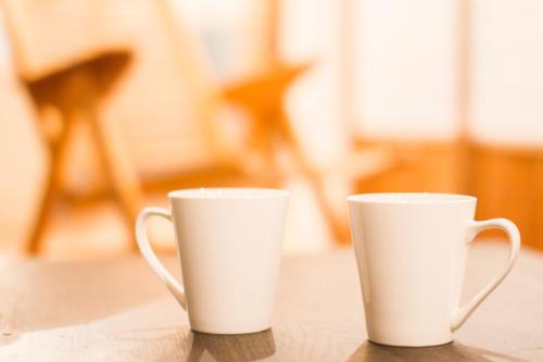 two white cups sitting on top of a table at Engawa in Tonosho