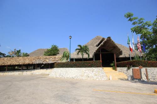 a building with thatched roofs and flags in a parking lot at Hotel Villa Mercedes Palenque in Palenque