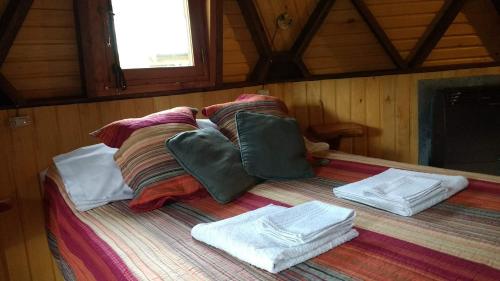 a bed in a room with towels on it at Domos Puelo in Lago Puelo