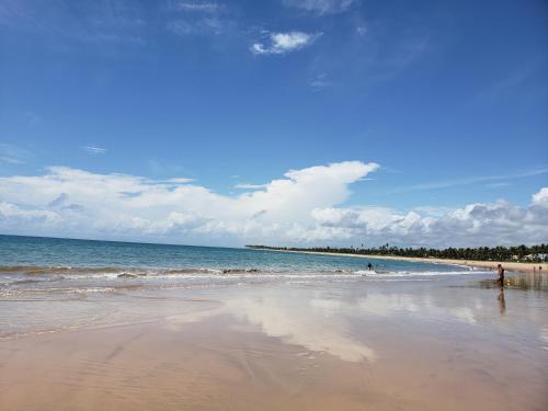 a beach with the ocean and people in the water at Genipabu Summer House Guarajuba in Guarajuba