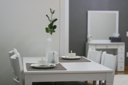 a white dining room table with two cups and a vase at Forest of Color Pension in Hongcheon