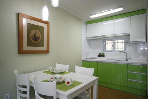 a kitchen with a white table and green cabinets at Forest of Color Pension in Hongcheon