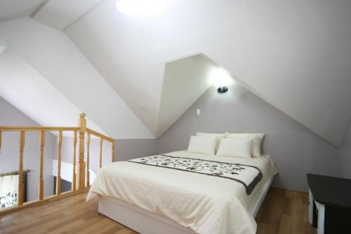 a bedroom with a white bed in a attic at Forest of Color Pension in Hongcheon