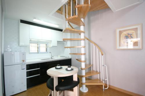 a kitchen with a spiral staircase and a stool at Forest of Color Pension in Hongcheon