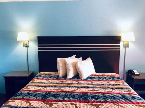 a hotel room with a bed with four pillows at Meridian Inn Oklahoma City Airport in Oklahoma City