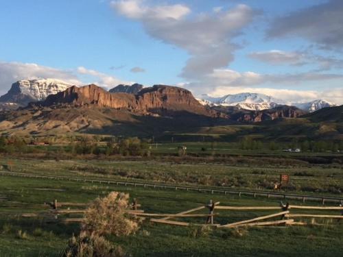 a field with a fence and mountains in the background at Eycat Lodging Company in Wapiti