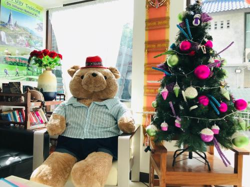 a large teddy bear sitting next to a christmas tree at Baan Sang Singh in Chiang Mai