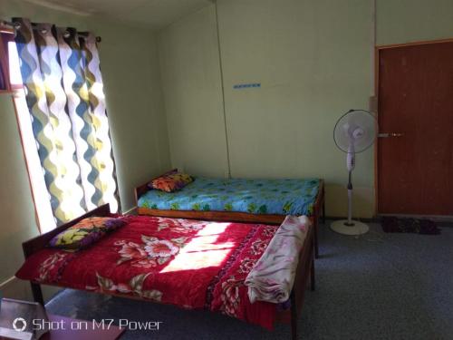 a bedroom with two beds and a fan and a window at Vamose Hlunbuang in Zuchhip