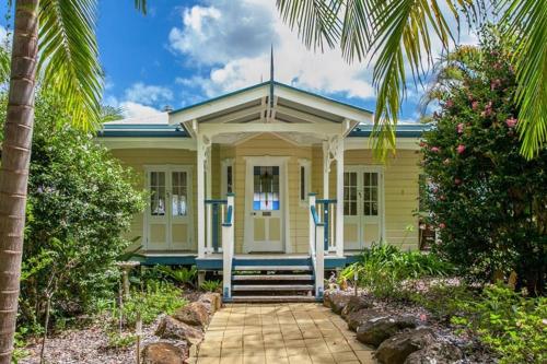a yellow house with palm trees in front of it at Valleydale cottage in Goonengerry