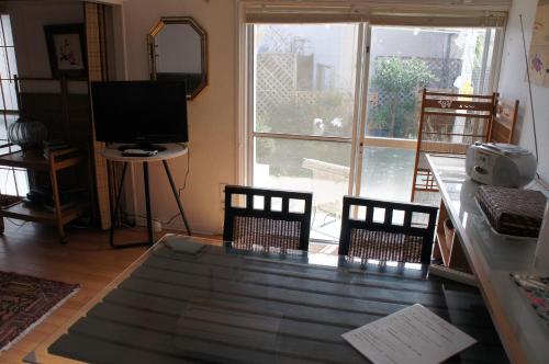 a living room with a table and chairs and a television at EMS Enoshima クラシックゲストハウス 寝室は個室 犬OK in Fujisawa