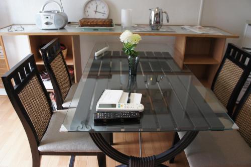 a glass table with a vase of flowers and a telephone at EMS Enoshima クラシックゲストハウス 寝室は個室 犬OK in Fujisawa