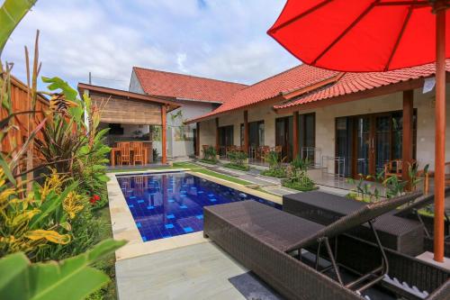 een huis met een zwembad en een rode parasol bij Rahma Guesthouse in Canggu
