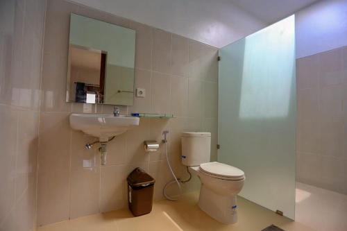 Un baño con inodoro, lavabo y espejo. en Rahma Guesthouse, en Canggu