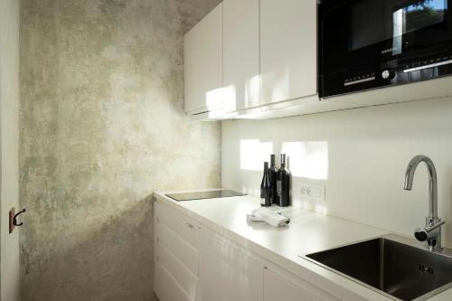 a kitchen with white cabinets and a sink at Villa Bergmann Suites Meran in Merano