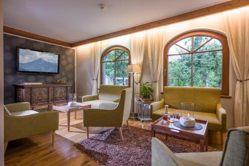 a living room with chairs and a tv and windows at derNeuwirt in Schwendau