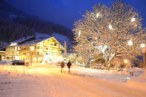 two people walking down a snow covered street at night at derNeuwirt in Schwendau