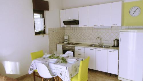 卡斯泰拉的住宿－瑪樂提克公寓，厨房配有一张桌子、黄色椅子和白色橱柜