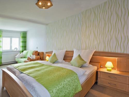 een slaapkamer met een groot bed en een groene deken bij Panoramaferienwohnung Bergwiese in Masserberg