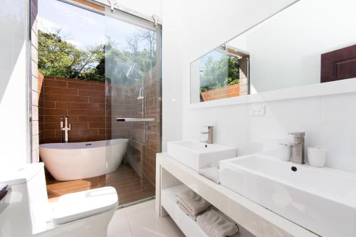 a white bathroom with two sinks and a tub at Kia Orana Villas and Spa in Rarotonga