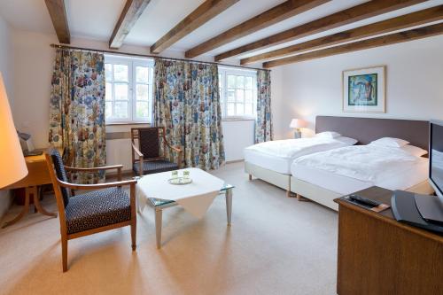 a hotel room with a bed and a desk and a tv at Romantik Waldhotel Mangold in Bergisch Gladbach
