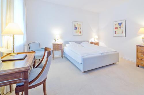 a hotel room with a bed and a desk and a desk at Romantik Waldhotel Mangold in Bergisch Gladbach
