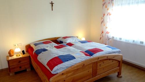 a bedroom with a wooden bed with a cross on the wall at Marienhof in Leibertingen