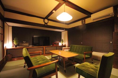 a living room with a table and chairs and a television at Fuji Time Traveler in Fujikawaguchiko