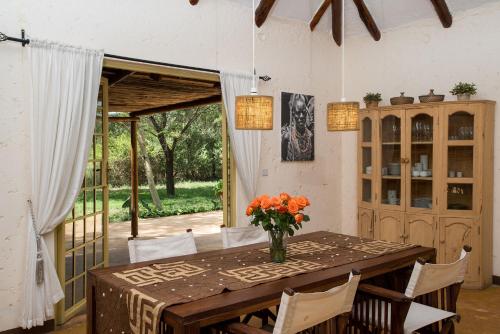 a dining room table with a vase of flowers on it at Kili Villa Kilimanjaro Luxury Retreat in Arusha