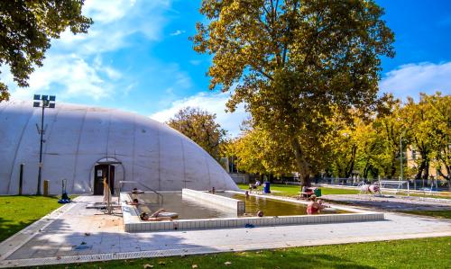 een koepel in een park met mensen die in een vijver spelen bij CVSE Clubház és Panzió in Cegléd