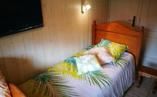 Bett mit einem Kopfteil aus Holz mit Kissen darauf in der Unterkunft La canopée in Mimizan